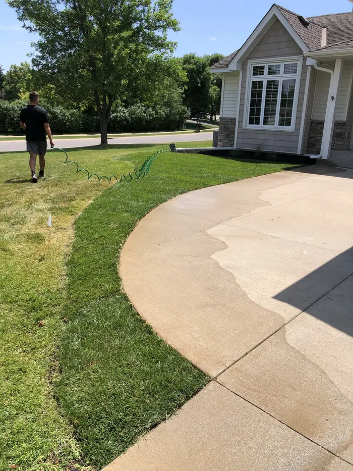Clean edge cut along a curved driveway in front of a house