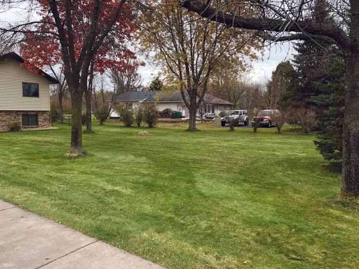 Lawn mowed in fall with red and yellow trees