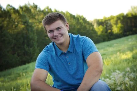 Jake, owner of Mow Me, sitting in a grassy field