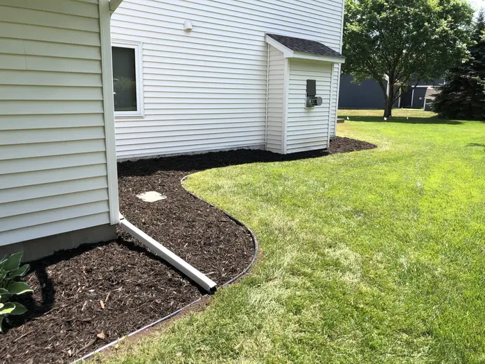 Curved mulch bed cut along the side of a white house