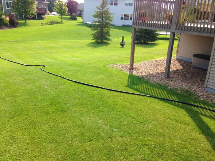 Edged mulch bed along a deck with a long green lawn