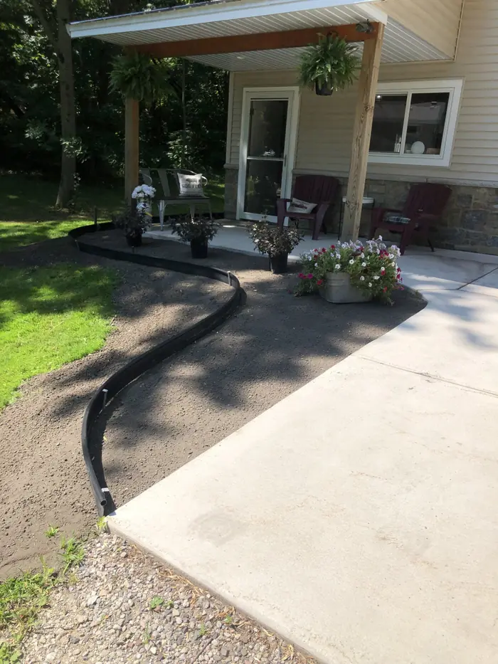 Black edging and mulch curving around a patio