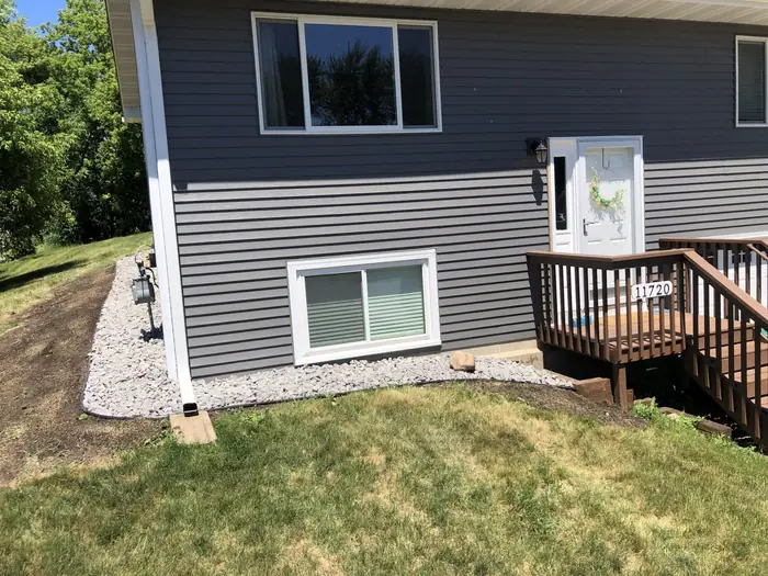 New rock bed along a gray-sided house next to a deck